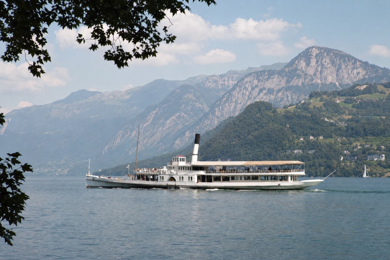 A paddle steamer crossing calm Lake Lucerne with mountains behind, no text, no logos, no people